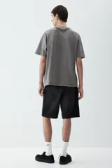 Remera gris de algodón de peso medio con efecto lavado, corte holgado, cuello redondo ribeteado acanalado, hombros caídos y bajo recto.