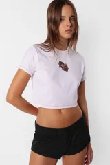 Remera corta blanca tipo baby tee, de cuello redondo y mangas cortas, confeccionada en jersey de algodón. Detalle de costuras rojas en toda la prenda y estampa de flecha con rosa en el delantero.