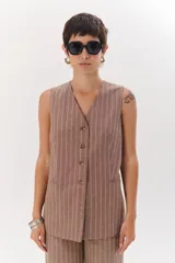 Chaleco gris con finas rayas verticales blancas, con cuello en V, cierre frontal con botones y bolsillos laterales.