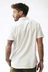 Camisa blanca de manga corta con cuello clásico y cierre frontal con botones.