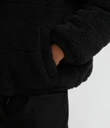 Campera puffer de sherpa color negro, con capucha, cierre frontal y regulador elástico en la cintura.