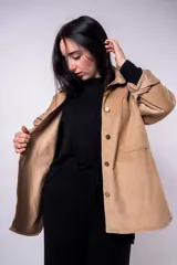 Sobrecamisa color beige de pana con cuello camisero, cierre frontal con botones a presión, dos bolsillos de parche en el pecho y corte holgado.