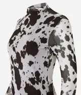 Blusa de mangas largas confeccionada en tule, con cuello alto y estampa animal print de vaca en blanco y negro.