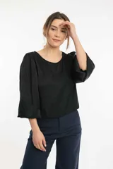 Blusa azul marino con cuello bote y mangas amplias con elástico en los puños.