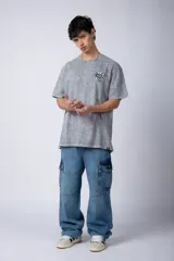 Remera gris con efecto acid wash, corte holgado y estampa frontal con una mano sosteniendo el mundo VCP.
