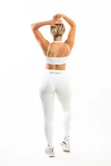 Conjunto deportivo blanco compuesto por un top con escote halter y calzas largas de tiro alto con bolsillos laterales.