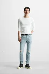 Pantalón de jean negro con corte skinny fit, cinco bolsillos, lavado con efecto roto y cierre frontal con cremallera y botón.