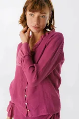 Blusa blanca de lino con botones de nácar, volados en el escote y mangas largas con puños acampanados. Corte recto y holgado.