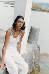 Top blanco de algodón con escote redondo y tirantes decorados con apliques de flores negras.
