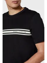 Remera negra de algodón regenerativo con cuello redondo, dos rayas horizontales blancas en el pecho, logo monotipo de Tommy Hilfiger en el pecho y bandera de Tommy Hilfiger bordada en la manga.