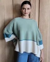 Buzo de punto con diseño de bloques de color negro, gris y beige. Tiene cuello redondo y mangas anchas tres cuartos.