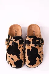 Zuecos con estampado de vaca en tonos camel y negro, con hebilla metálica ajustable y plantilla anatómica.