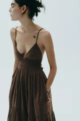 Vestido midi marrón con escote en V, tirantes finos ajustables y espalda descubierta con lazadas.