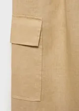 Pantalón cargo color beige de lino, corte recto y tiro medio. Cuenta con cintura elástica ajustable con cordón, bolsillos laterales y bolsillos de parche con solapa en las piernas.