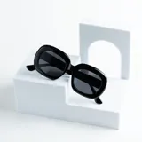 Lentes de sol negros con forma rectangular redondeada y protección UV400.