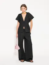 Blazer negro de lanita viscosa con cuello mao y mangas ranglan abullonadas tipo balloon con frunces en la unión con el cuello. Incluye pinza lateral que mejora el calce en la sisa, bolsillos ojal con tapa y cierre con broche bombé super black.