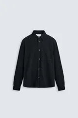 Camisa negra de algodón con cuello abotonado, manga larga con puños abotonados, corte regular fit y bolsillo de parche en el pecho. Colección especial Origins.