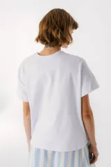 Remera blanca de algodón con estampado de tres jarrones con flores rojas y la frase "The Flowers Club" en azul.