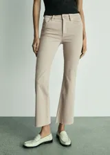 Pantalón de jean color beige, de corte flare y tiro alto.