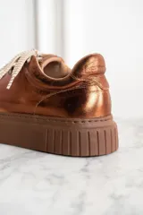 Zapatillas acordonadas color cobre metalizado, con suela marrón de goma.