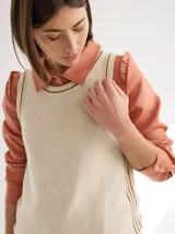 Camisa blanca de lino con cuello clásico, abotonada al frente con botones de madera, mangas largas con volados en los hombros y corte femenino.