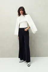 Pantalón de jean negro de corte ultra wide, tiro medio y detalles metálicos en la cintura.
