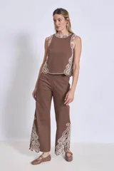 Pantalón blanco de corte ancho con bordados calados en forma de hojas en el ruedo.