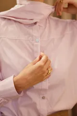 Camisa de algodón a rayas verticales rosas y blancas, con cuello alto y lazo grande en el cuello.