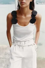 Top blanco de algodón con escote redondo y tirantes decorados con apliques de flores negras.