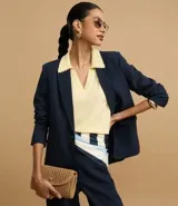 Blazer azul marino de corte sastrero, con solapas con detalle de puntilla en color crema, cierre con un botón dorado y bolsillos delanteros con solapa.