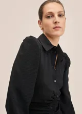 Vestido camisero midi negro con textura de mini rombos, corte entallado, cuello camisero, cierre frontal con botones, mangas largas abullonadas y frunces en la cintura.