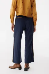 Pantalón de vestir color marrón con corte recto y cintura alta. Presenta una fina cinta roja a modo de cinturón.