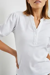 Remera blanca de algodón con mangas cortas abullonadas y cuello henley con tapeta de botones.