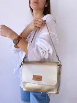 Bandolera dorada de cuero con forro de tela, bolsillo interno, correa larga con cadena desmontable y correa corta de cuero desmontable.