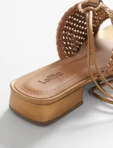 Sandalias bajas color cobre con capellada tejida y tiras finas para atar al tobillo.