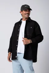 Camisa negra de manga larga, corte oversize, con un bolsillo en el pecho y costuras a contraste.