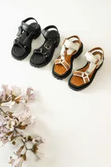 Sandalias con plataforma color marrón, con tiras de cuero color blanco y marrón con hebillas metálicas.