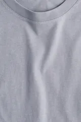 Remera gris de corte recto en punto suave de algodón con cuello redondo ribeteado y hombros ligeramente caídos.