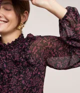 Blusa de chiffon negra con estampado floral liberty en tonos rosados, cuello alto con lastex y volados en los hombros. Mangas largas con puños ajustados.