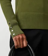 Suéter de punto color verde, con cuello barco, mangas largas y textura acanalada.