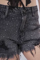 Short de jean negro lavado con efecto desgastado y roturas. Presenta apliques de strass o brillos distribuidos por toda la prenda y terminación de ruedo deshilachada.
