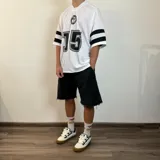 Remera negra estilo fútbol americano con cuello en V y mangas cortas con tres rayas blancas. Estampado frontal con logo y número 20 en blanco.