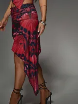 Conjunto de top asimétrico y falda pareo con estampado abstracto en tonos rojo y negro.