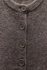 Chaqueta de punto color marrón con aberturas laterales y cierre frontal con botones.