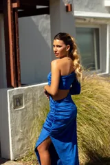 Vestido largo de terciopelo azul eléctrico, con un hombro descubierto, una manga larga, abertura lateral y falda con frunces.