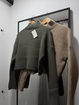 Sweater corto color beige, de cuello alto y tejido de punto acanalado.