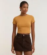 Blusa femenina color mostaza, modelo baby tee, confeccionada en algodón con elastano. Presenta un diseño ajustado, cuello redondo, manga corta y sisa desplazada.