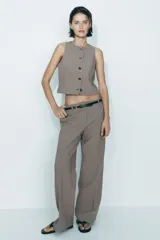 Pantalón de tiro alto con estampado a cuadros en tonos beige y marrón, con bolsillos delanteros y falsos bolsillos traseros. Incluye cinturón marrón con hebilla metálica.