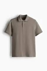 Remera polo color marrón de piqué de algodón, de corte regular fit, con cuello clásico, tapeta de botones, mangas cortas y bajo recto con aberturas laterales.