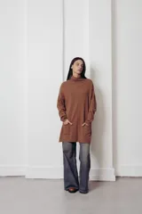 Sweater oversized color marrón con cuello alto y bolsillos frontales.